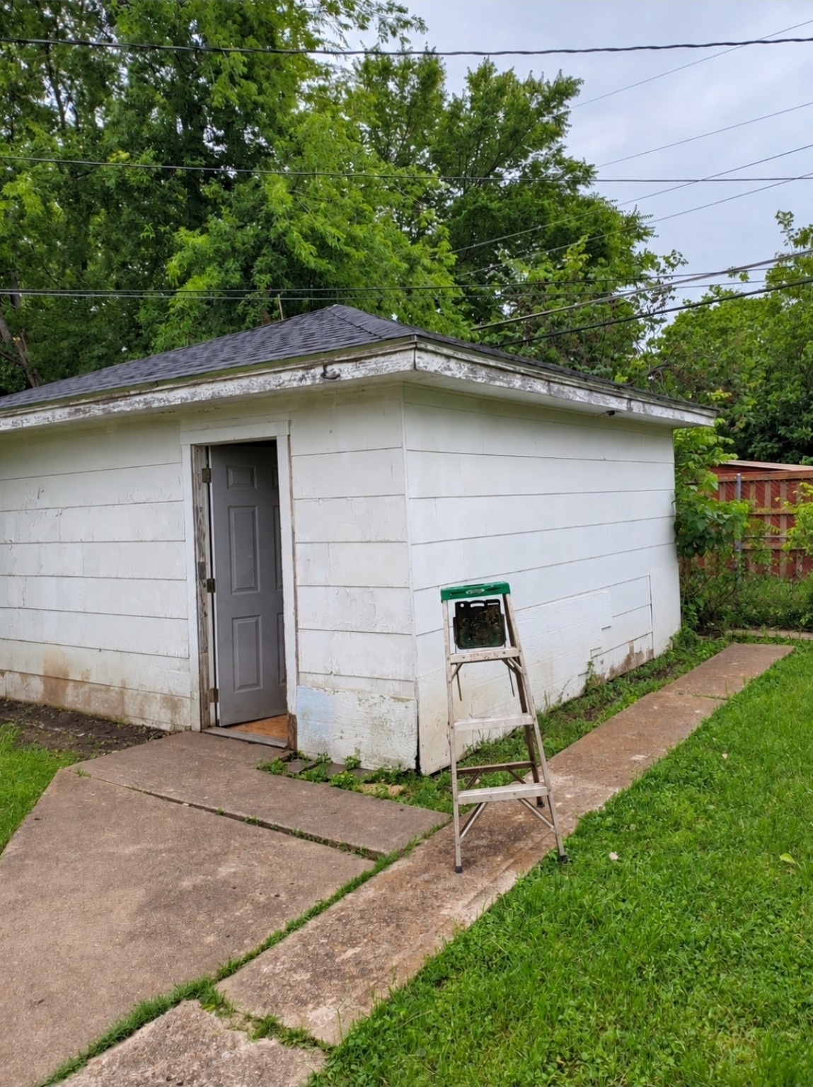 Before: white detached garage with weathered siding and peeling fascia paint.